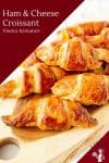 A close up of a stack of croissants on a wooden tray.