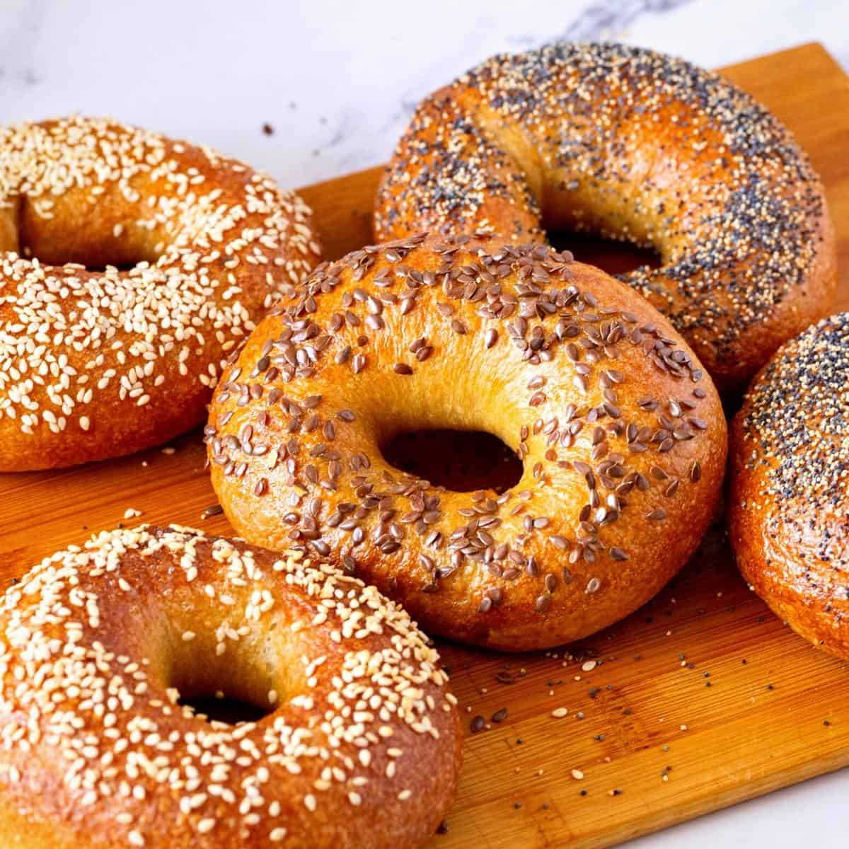 Different types of bagels on a wooden board.