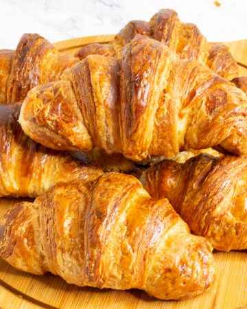 Stack of Croissants on a wooden board.