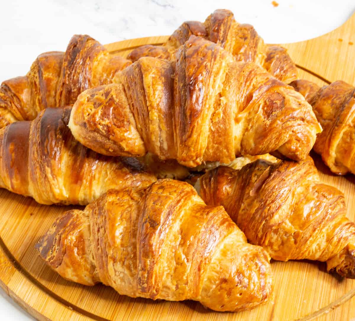 Stack of Croissants on a wooden board.
