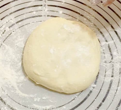 Roll the dough for pizza with white sauce