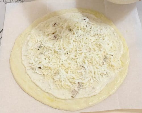 Spread the cheese and mushrooms on the pizza dough