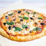 A pizza with olives and onions sitting on top of a wooden board.