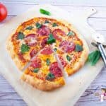 A sliced pepperoni pizza pie on a wooden tray.