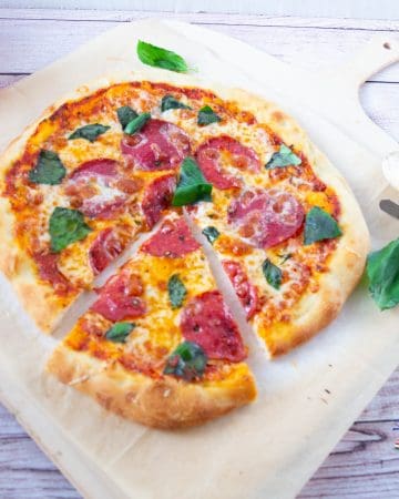 A sliced pepperoni pizza pie on a wooden tray.