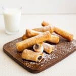 A stack of filo chocolate cigars on a wooden board.