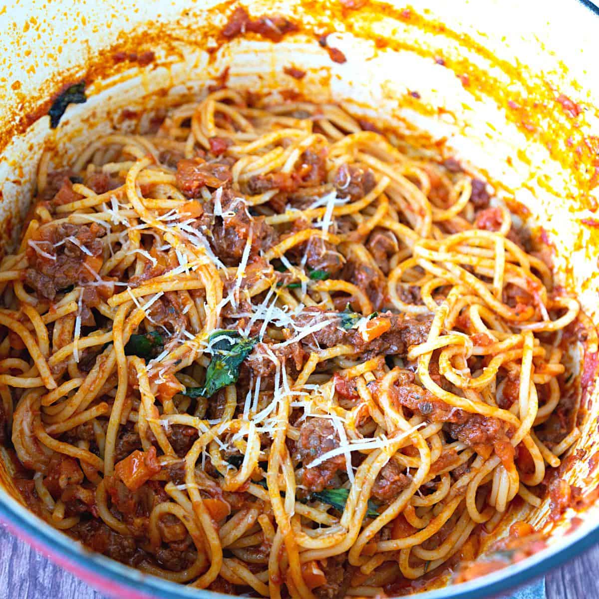 A pot with bolognese sauce mixed with spaghetti.