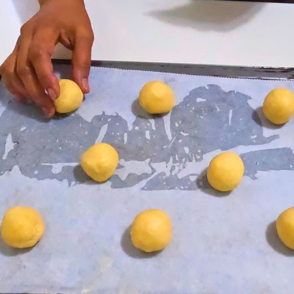 Condensed milk cookies dough balls for baking on a tray.