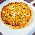 A sliced pizza pie on a wooden tray.