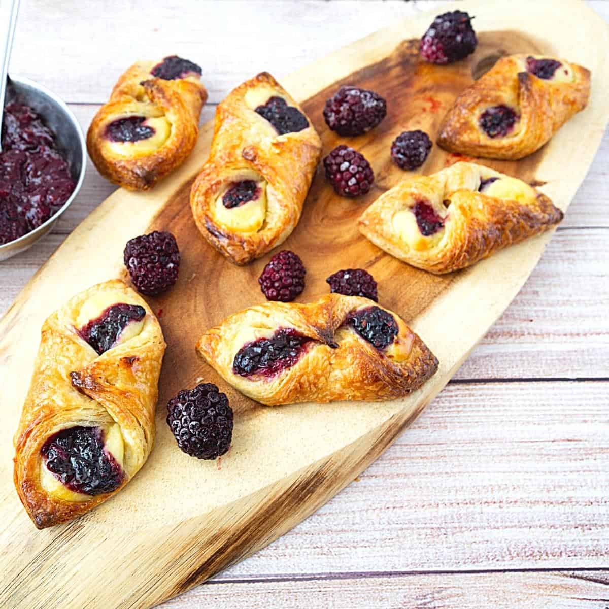 Danish pastry shaped cylinders on a wooden board.