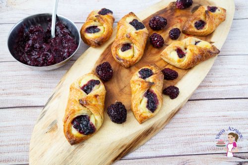 Danish pastry with berries on a wooden tray.