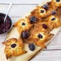 Danish pastry pin wheels with berries on a wooden tray.