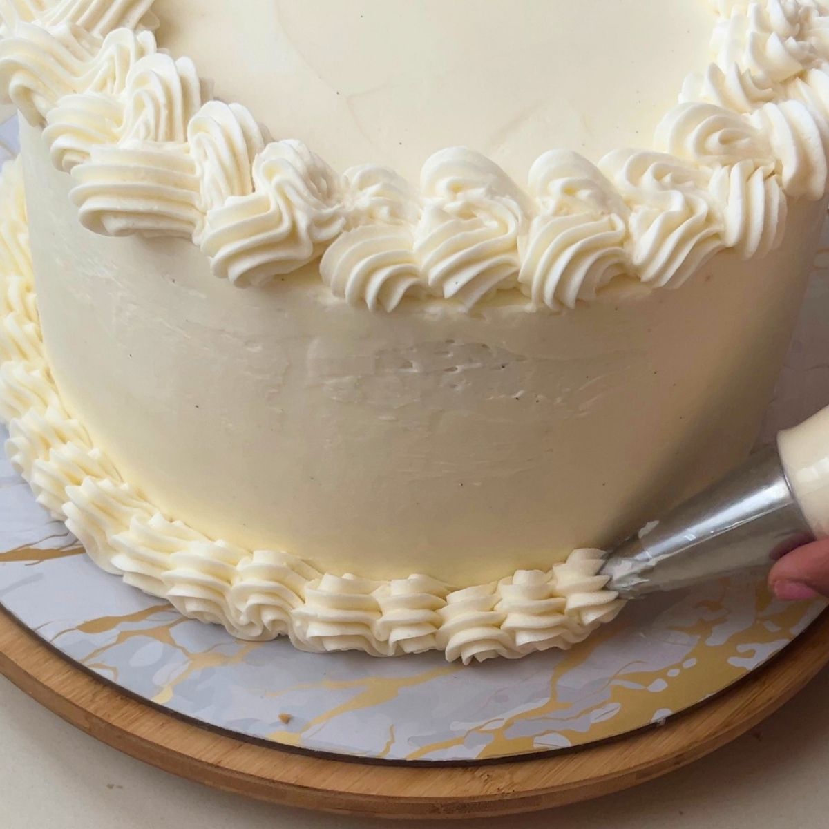 Piping border frosting on the funfetti cake.