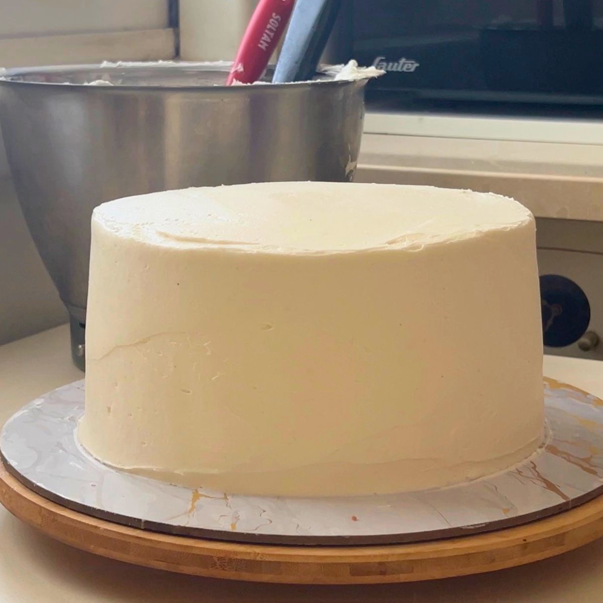 A frosted funfetti cake on the cake board.