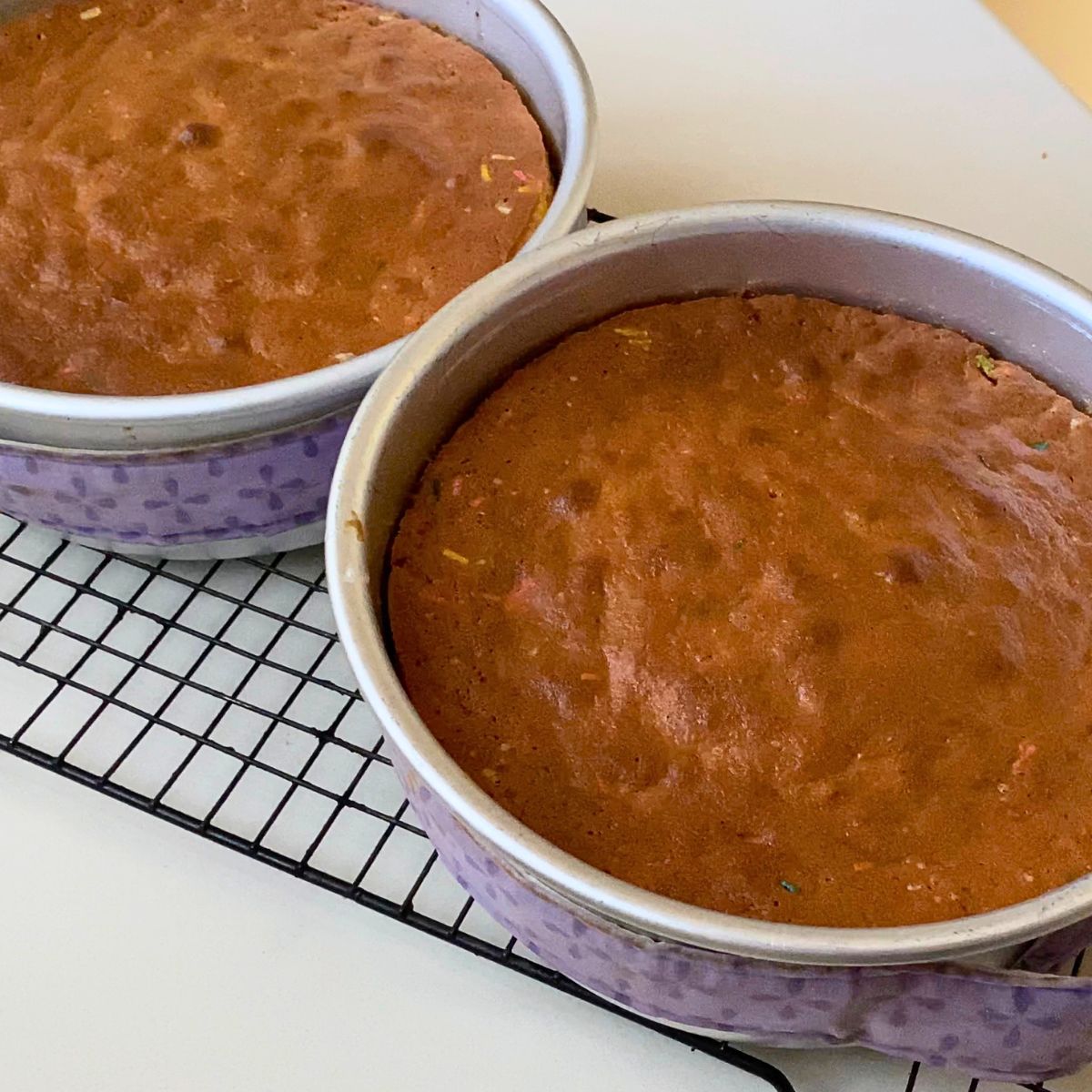 Two baked funfetti cakes in cake pans.