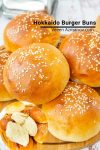 A close up of a stack of hamburger buns on a wooden tray.