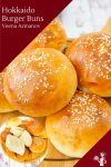 A close up of a stack of hamburger buns on a wooden tray.