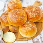 Hamburger buns on a wooden board.