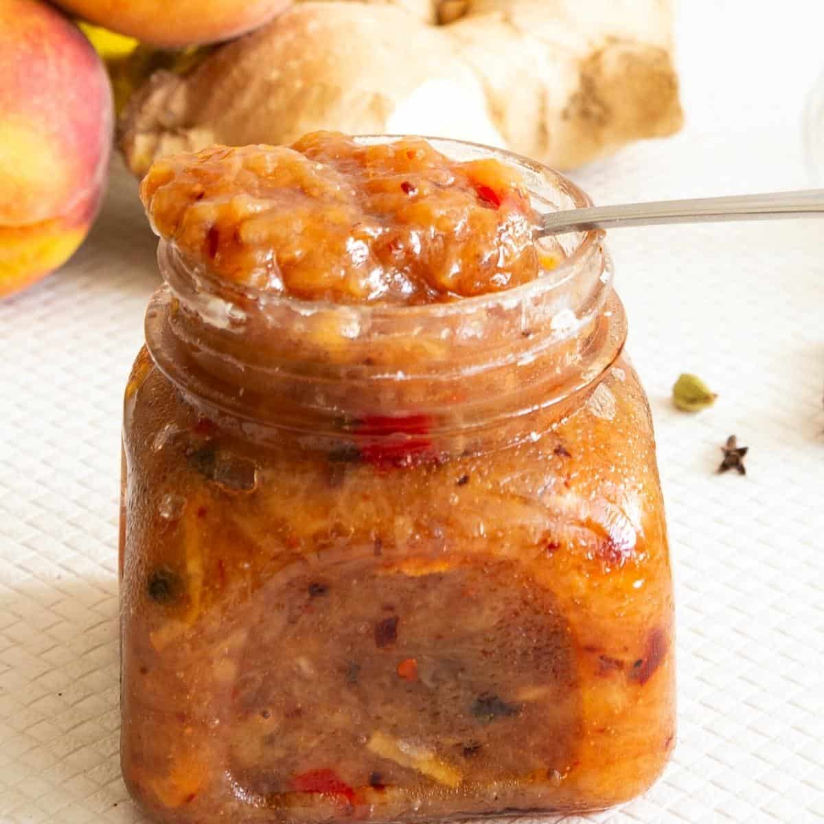 peach chutney in a jar with spoon.