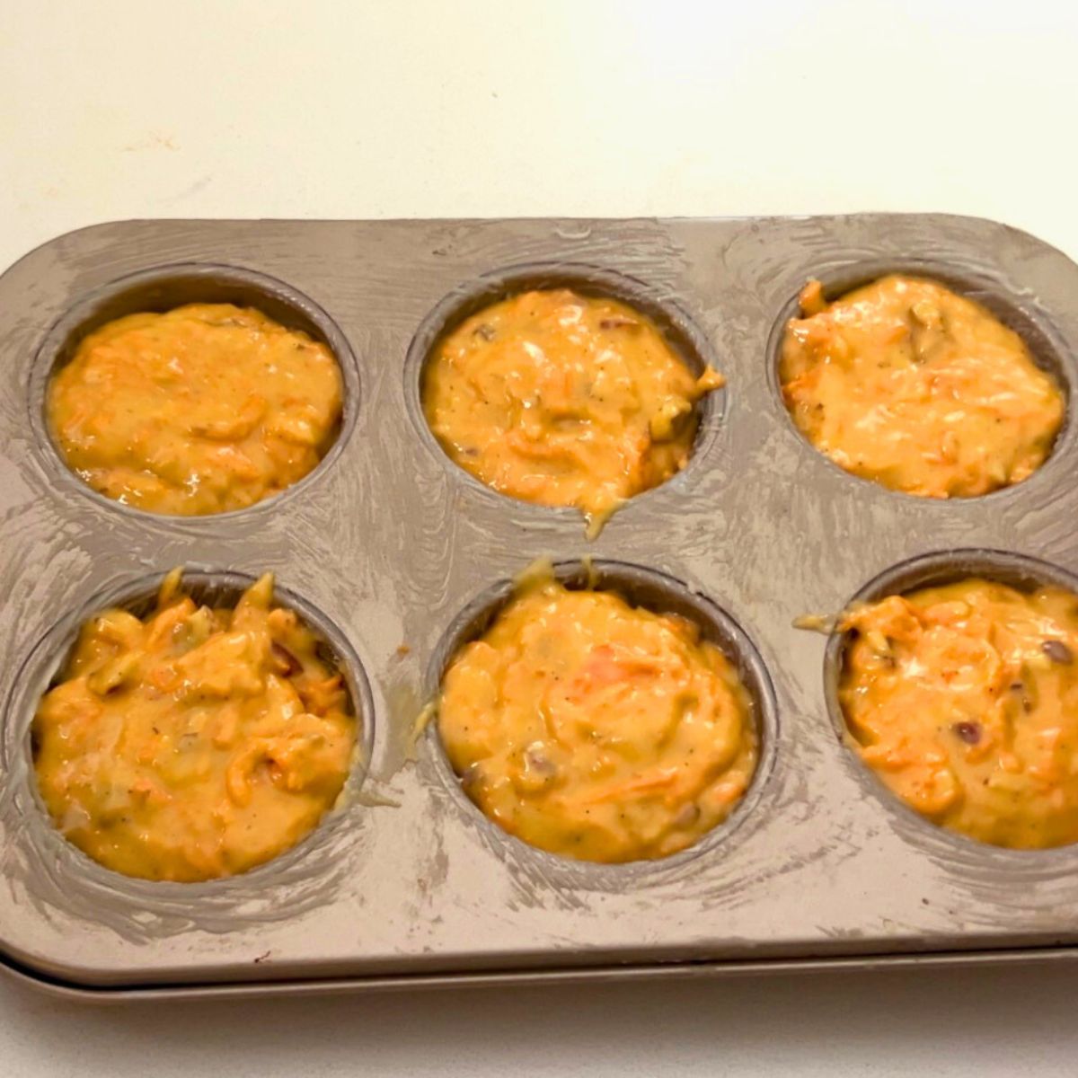 Muffin pan with carrot cake muffin for baking.