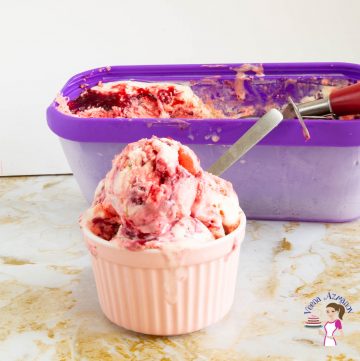 Raspberry ice cream in a small bowl with a spoon.