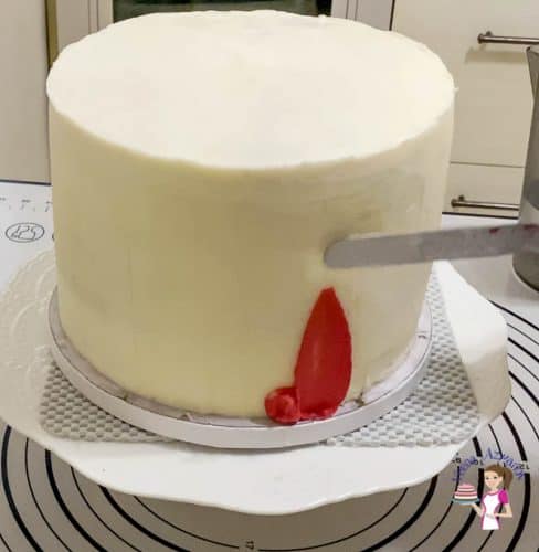 Use red buttercream to create a smear effect on the side of the cake