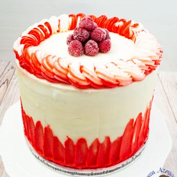 A raspberry white cake on a cake stand.