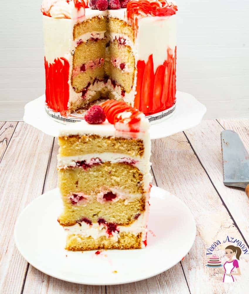 A slice of a raspberry white cake on a cake stand.