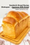 A loaf of white bread on a wooden cutting board.