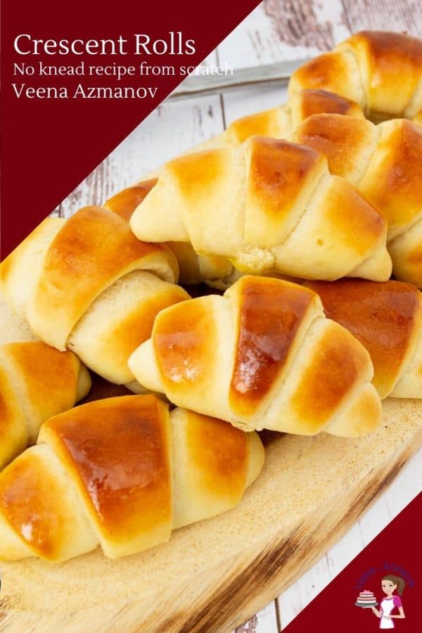 A stack of soft crescent rolls on a wooden tray.