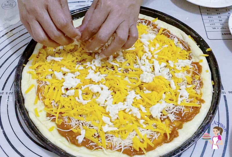 Sprinkle generous amount of cheese on the pizza