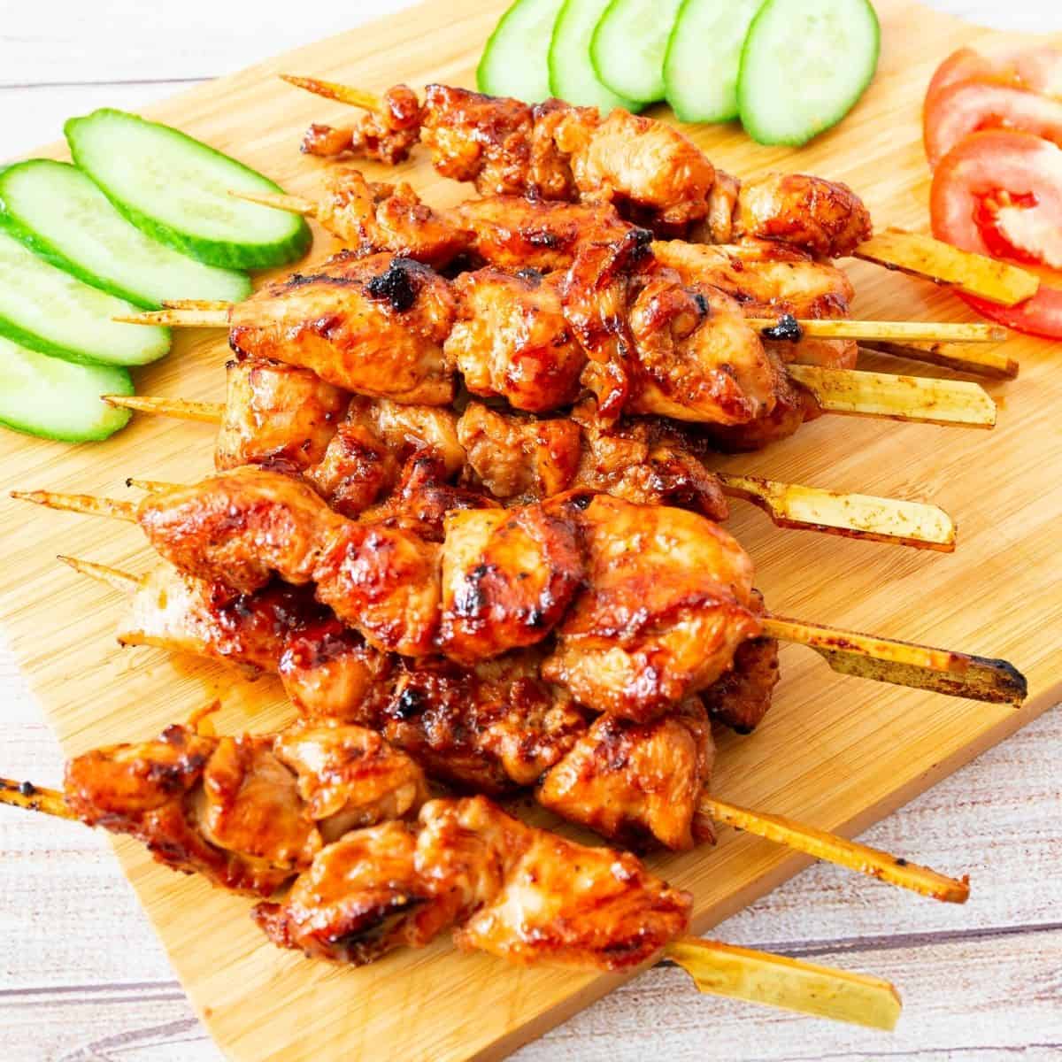 A board with glazed chicken skewers.