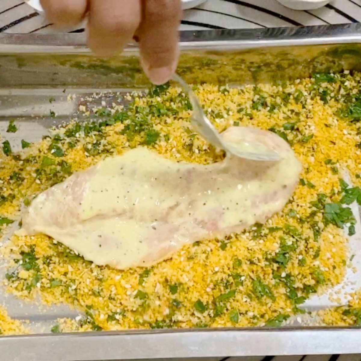 Coating the chicken breast in breadcrumb mixture.