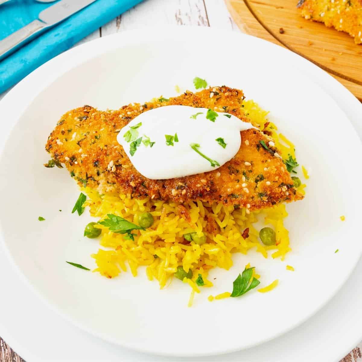 A plate with breaded chicken and turmeric rice.