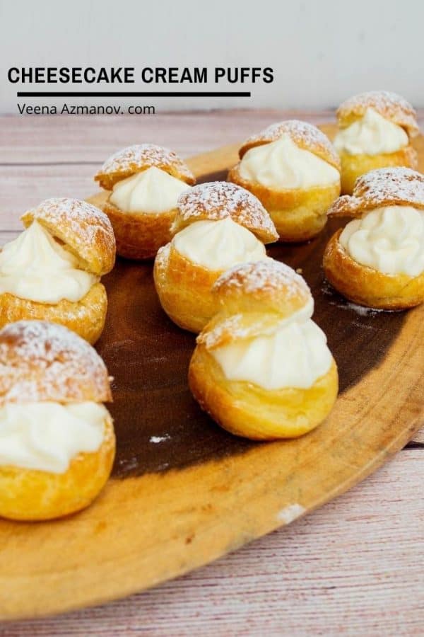 Cheesecake cream puffs on a wooden tray.