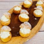 Cheesecake filled cream puffs on a wooden board.