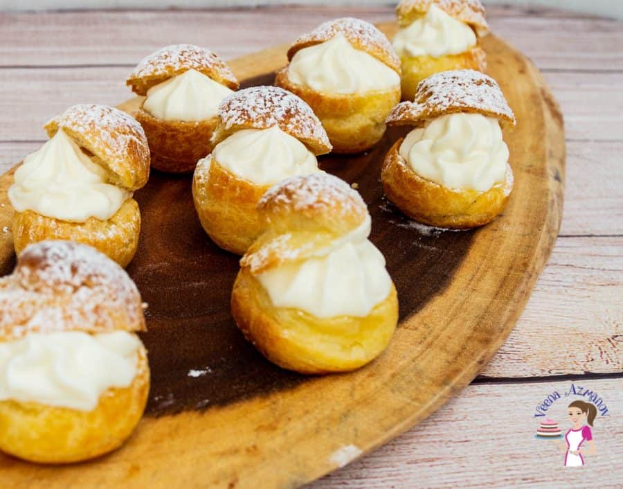 Cheesecake cream puffs on a wooden tray.