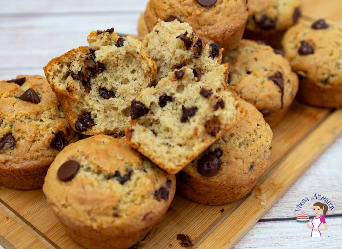 A close up of a stack of chocolate chip muffins on a wooden board.