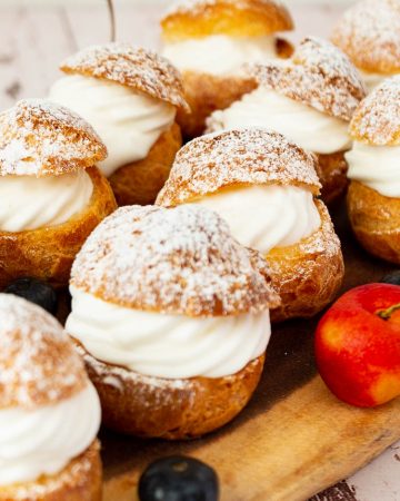 Cream puffs on a wooden tray.