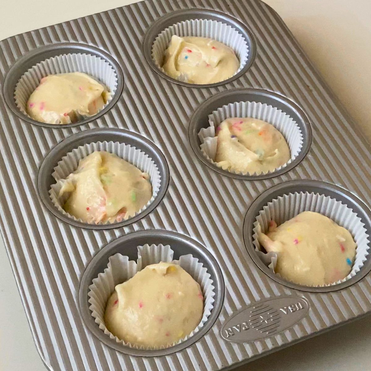 A muffin pan with funfetti cupcake batter.