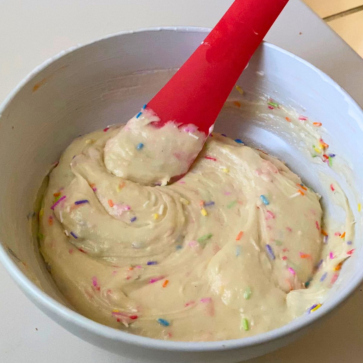 A white bowl with funfetti cake batter.