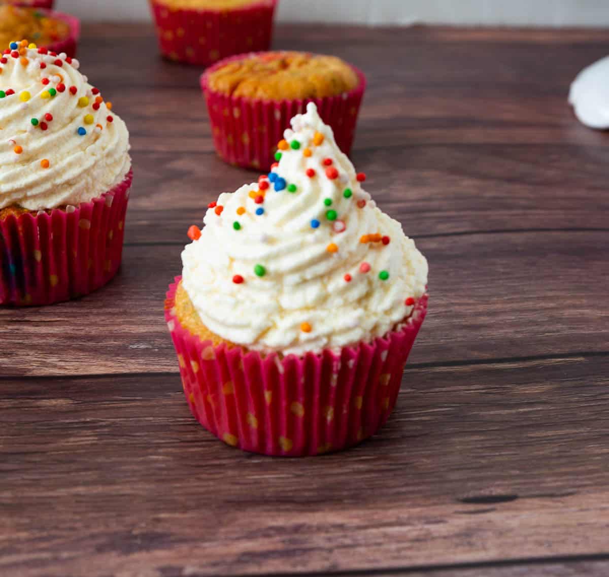 A funfetti cupcake on a wooden table.