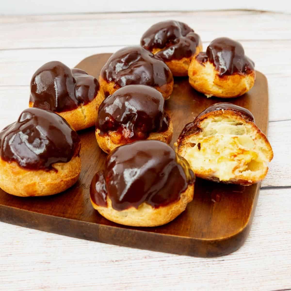 A wooden board with pastry cream stuffed profiterole.