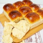 A wooden board with dinner rolls.