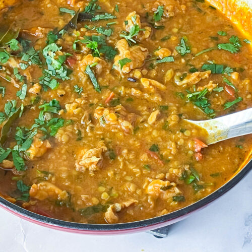 A skillet with lentils cooked with chicken.