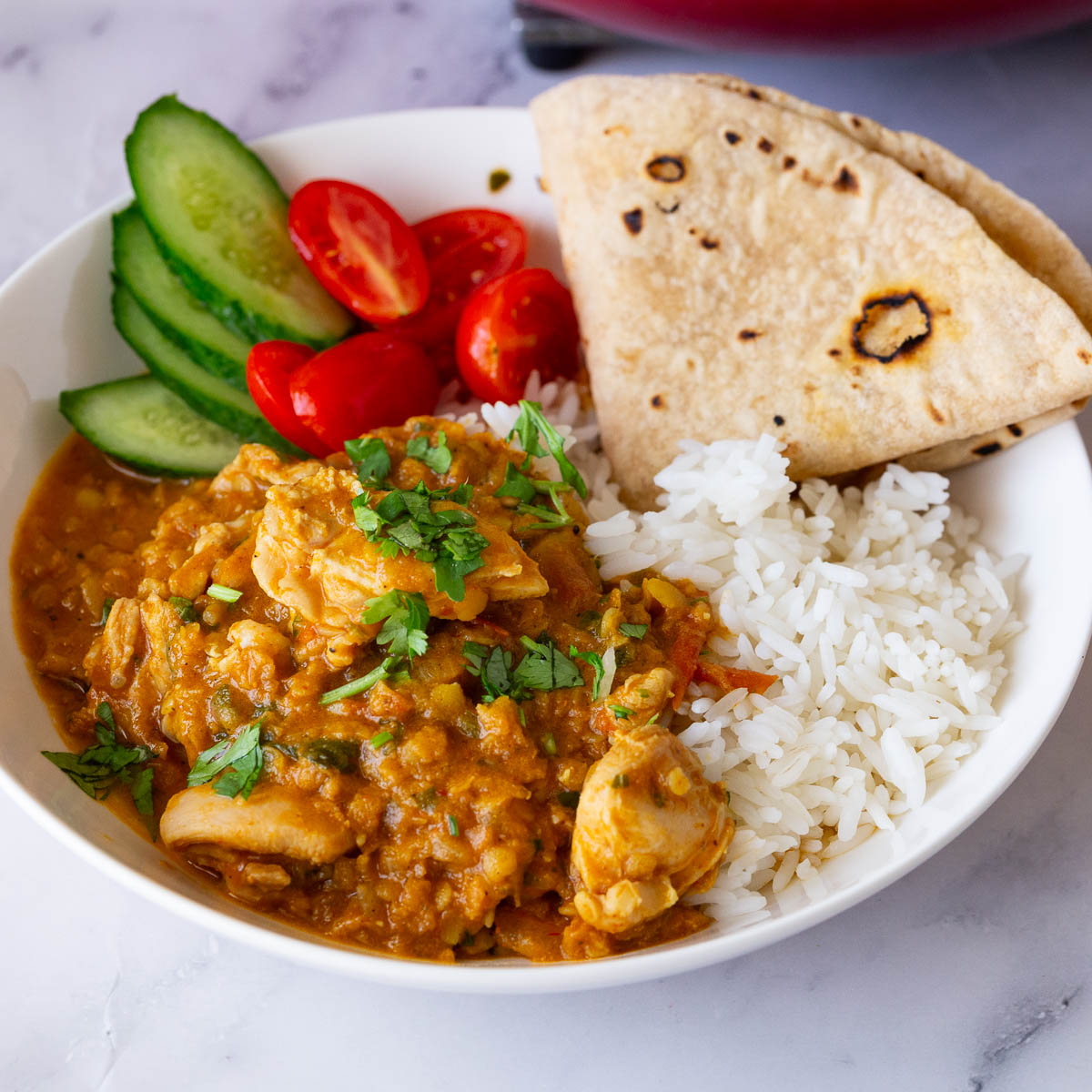 A white plate with rice lentils and chicken.
