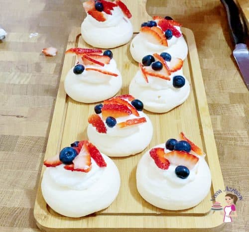Top each pavlova with fresh cream, strawberries and blueberries