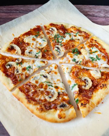 Sliced mushroom pizza on a wooden board