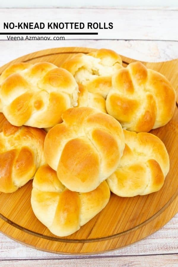 A stack of knotted dinner rolls on a wooden plate.