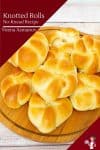 A stack of knotted dinner rolls on a wooden plate.